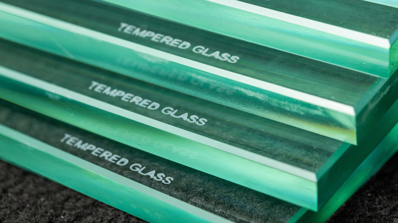 Multiple panes of equally thick glass are stacked on each other with the inscription 'tempered glass' on all of them