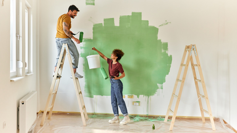 couple painting a room green