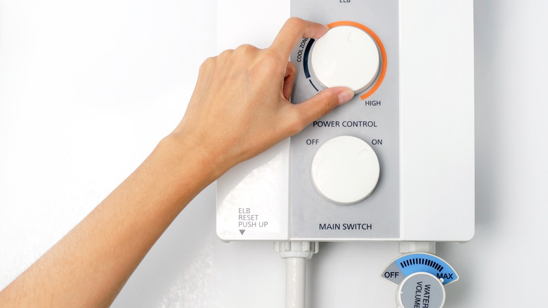 hand adjusting water heater temperature