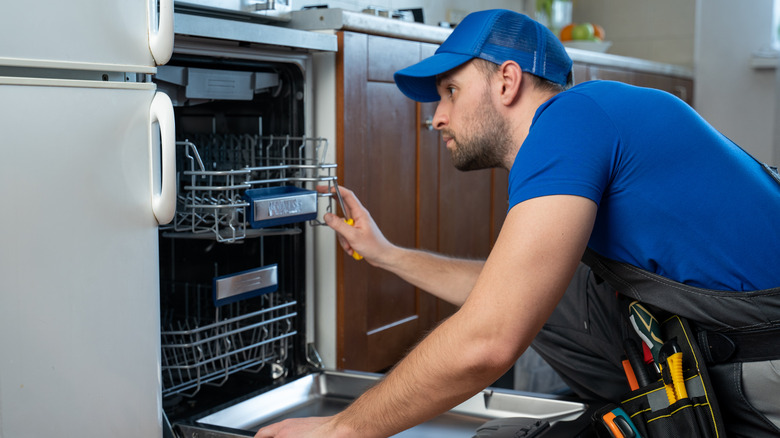 repairman looking in dishwasher