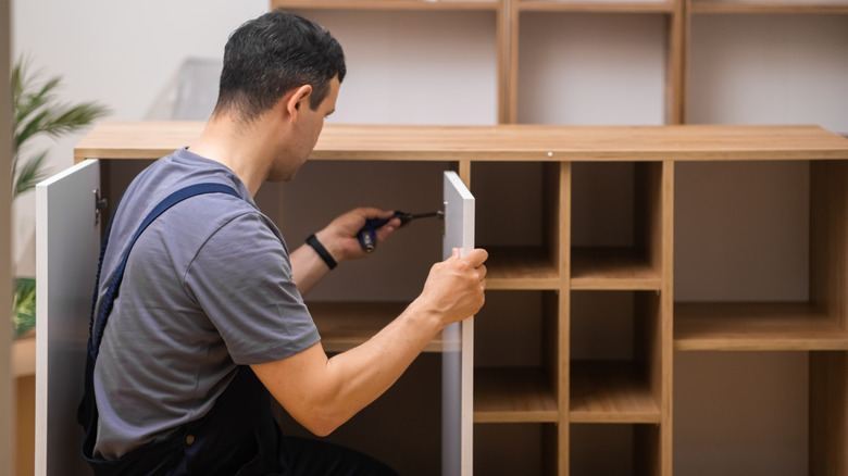 A worker installing kitchen cabinets