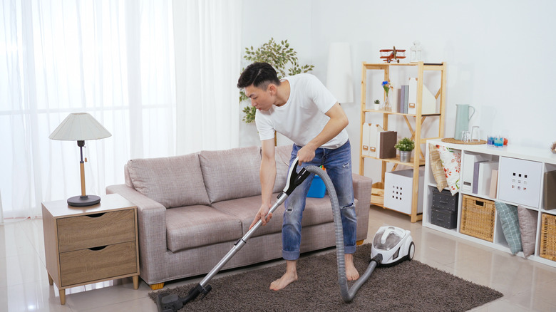 man vacuuming living room rug