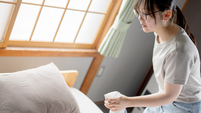 woman spraying pillow and bed