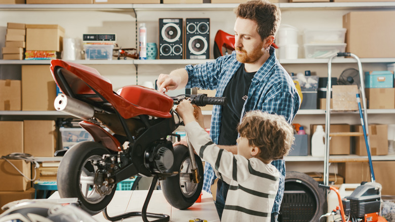 Man and boy in a garage working on a motorcycle