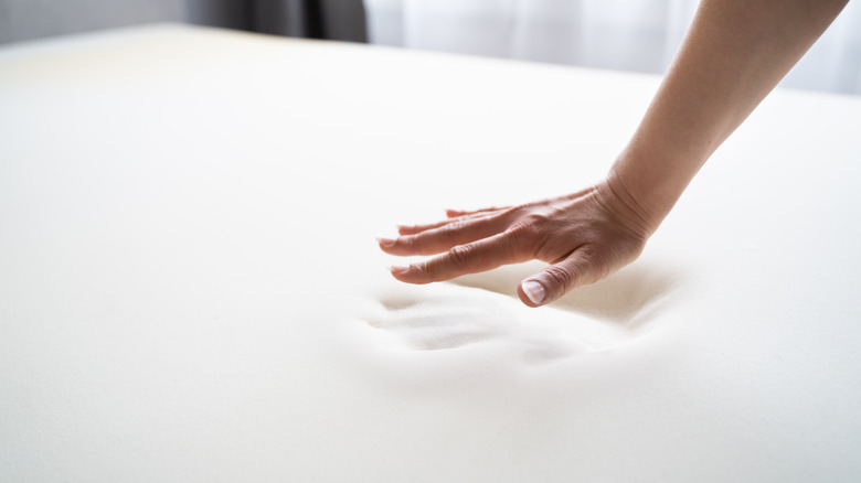 person testing memory foam with hand