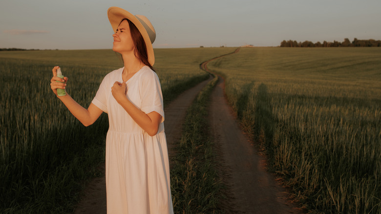 Woman spraying herself to avoid bug bites