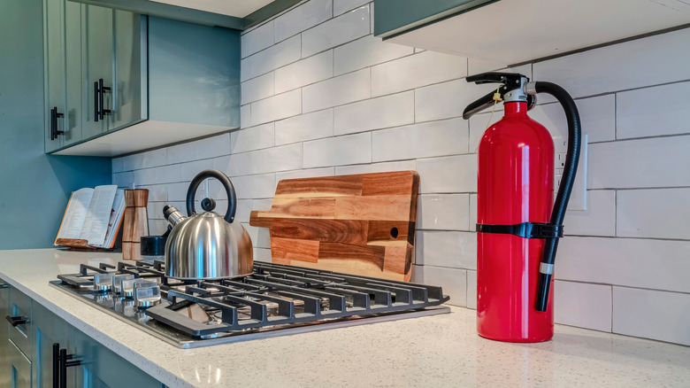 A fire extinguisher on the counter next to a gas stovetop