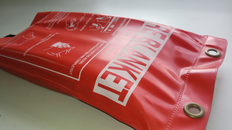 A red fire blanket pouch lying on a light grey surface