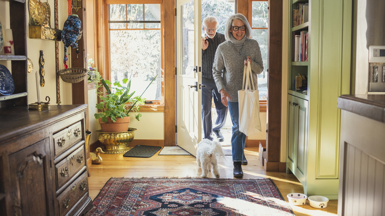 A couple and a dog enter an older home's entryway