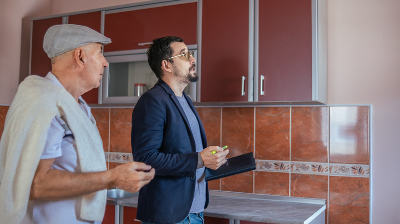 Two men inspecting an older home's kitchen