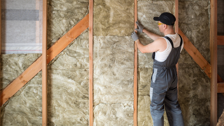 A construction worker adding insulation to the walls of a home