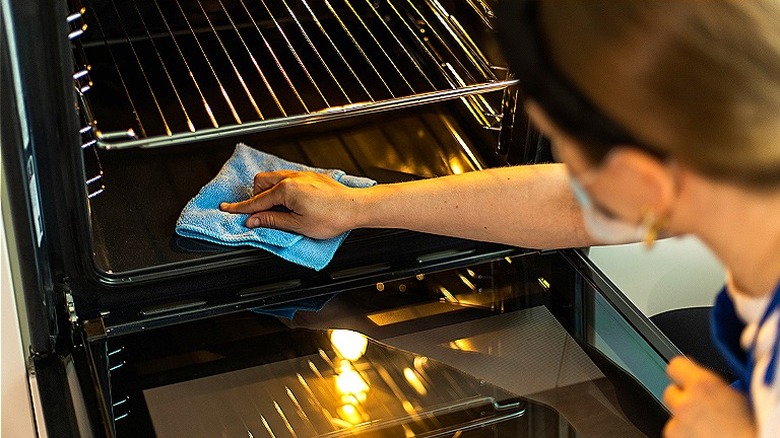 Person cleaning oven with rag