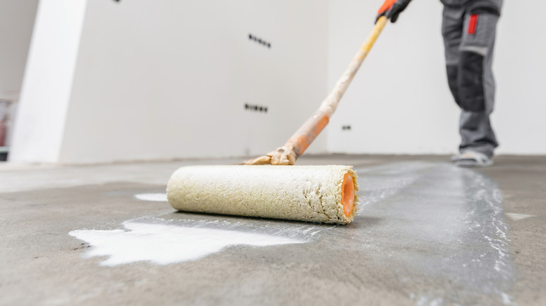 A person applying primer to a concrete floor