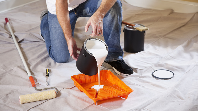 person pouring paint in roller tray