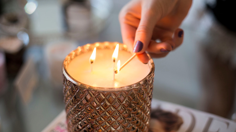 person lighting three wick candle