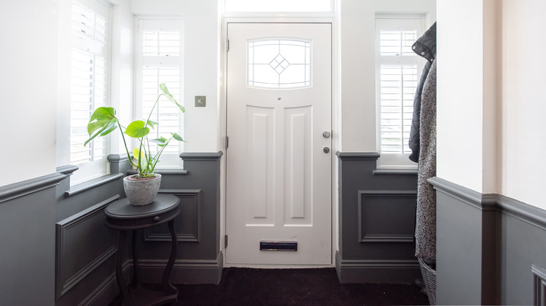 A doorway area decorated with a plant table and a coat rack