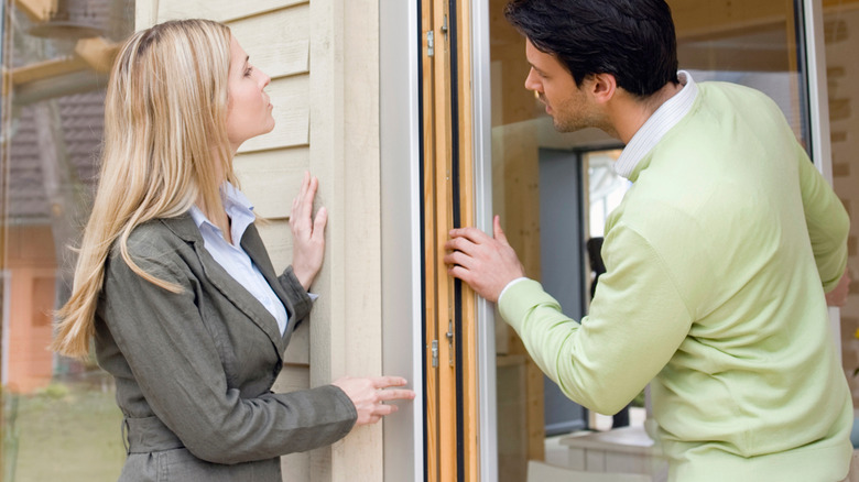 Two people are checking a door hinge