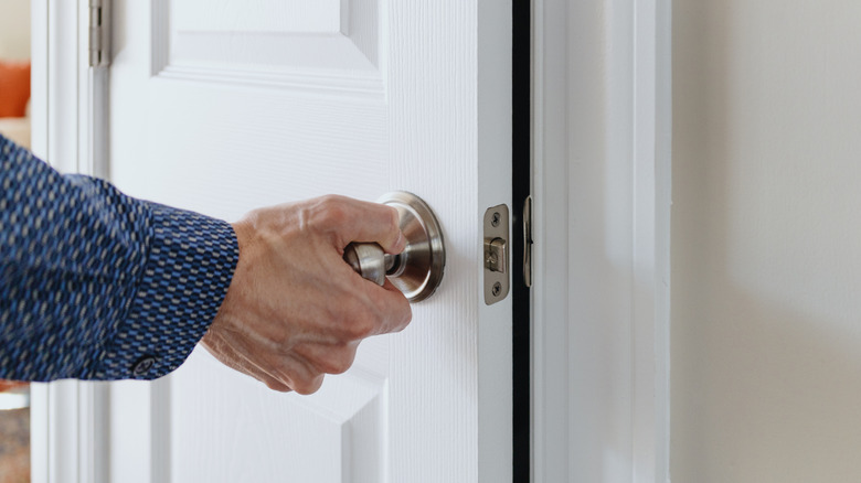 A person is opening a door inside a house