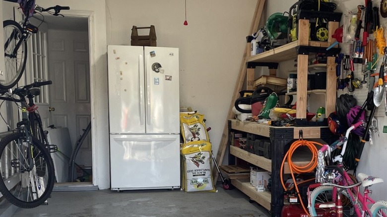 Garage with a white fridge inside it and tools on the walls