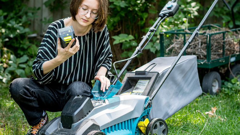 Woman changing battery on lawnmower