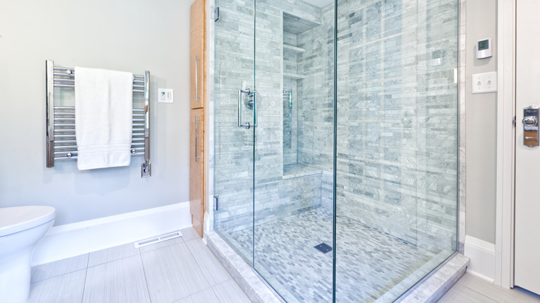 A mosaic tiled shower with glass surround