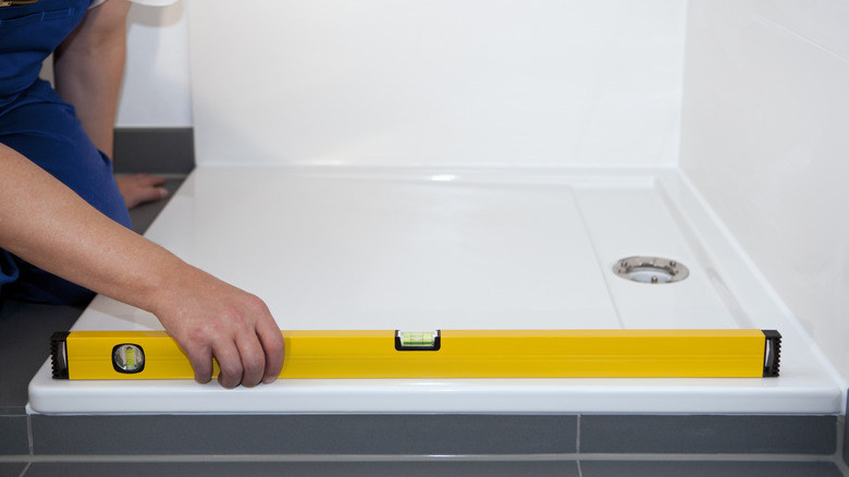 A man installs the base of a shower