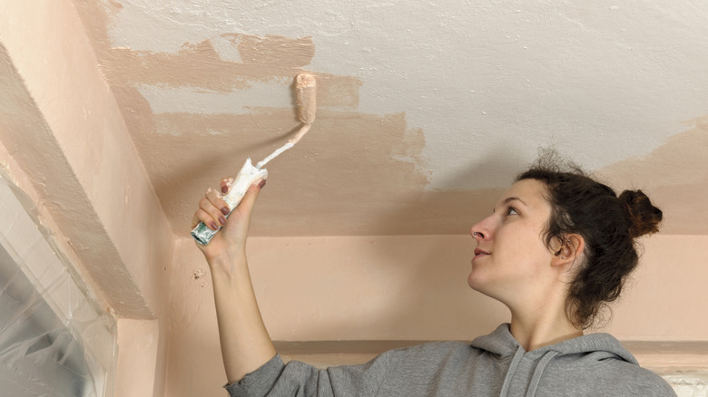 Woman painting her ceiling