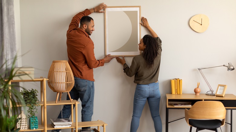 couple hanging picture on wall