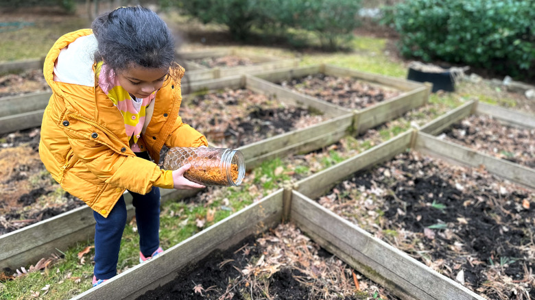 Girl adding compost to garden