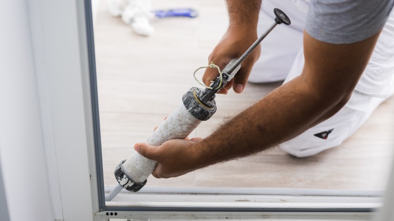 Sealing cracks with caulking gun 