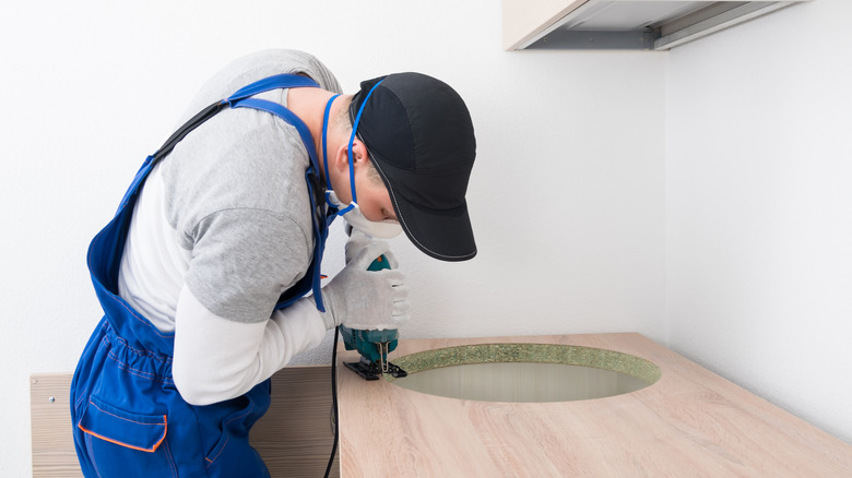 A person adding a hole to a countertop