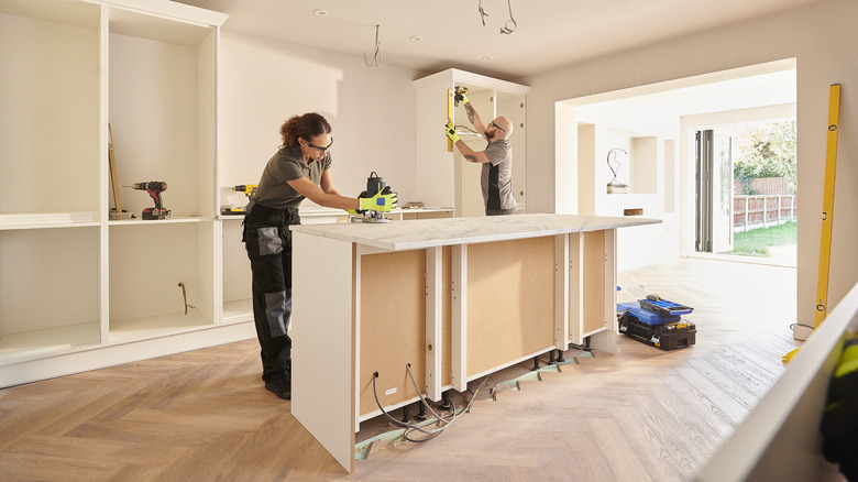 Two people are working to remodel a kitchen