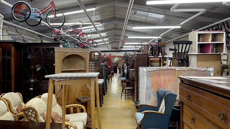 Furniture aisle of thrift store with many wooden items