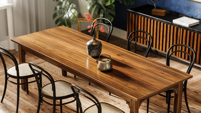 wood dining table with six chair and a flower vase and kettle on the table