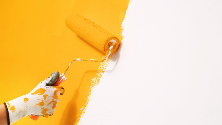 Person painting wall yellowish orange