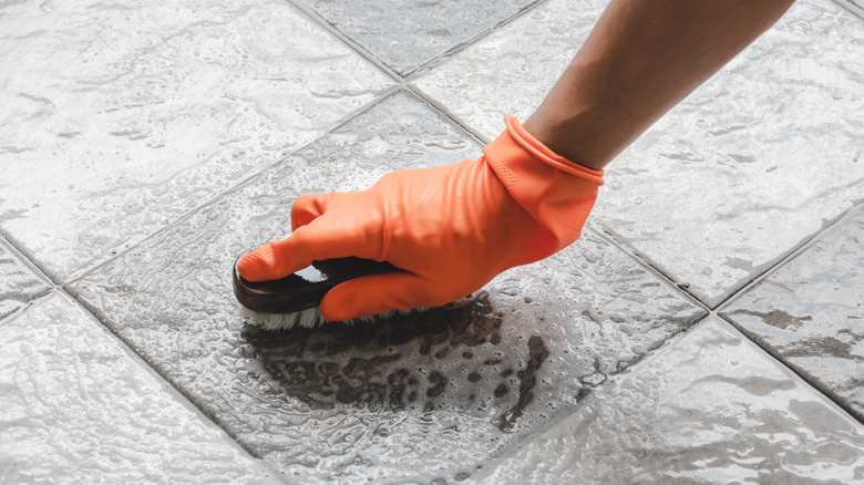 Man scrubbing floor grout