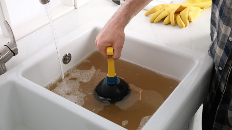 Person plunging a clogged sink