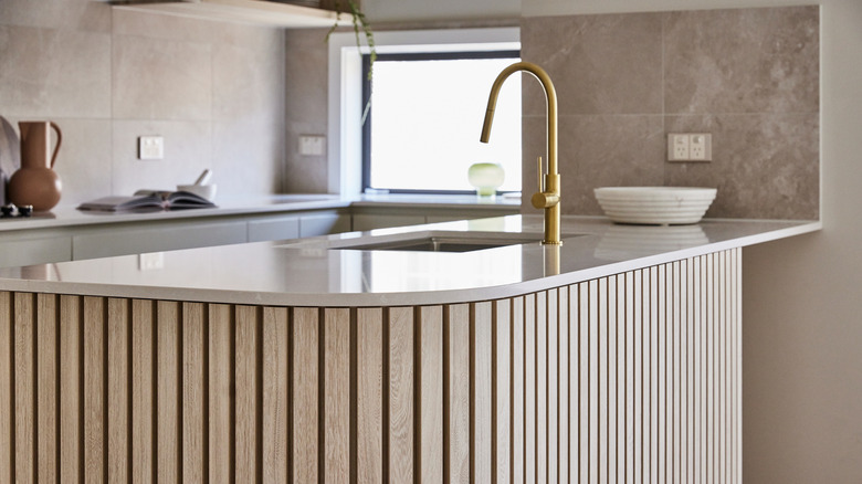 beige kitchen with wooden slatted kitchen island with sink in the middle