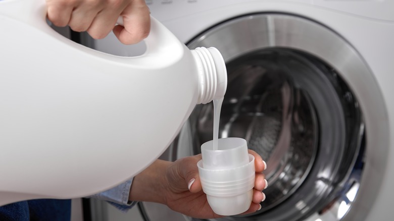 Woman pouring liquid detergent in cup