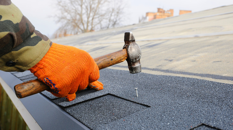 Hammering nail into asphalt roof