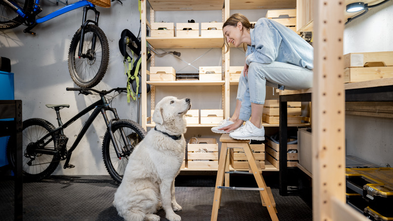 Lady talking to her dog in garage with wooden shelf