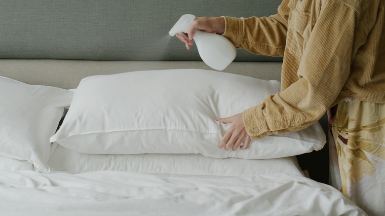 Person spraying bed pillows