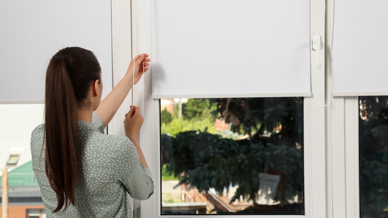 woman pulling down roller shade