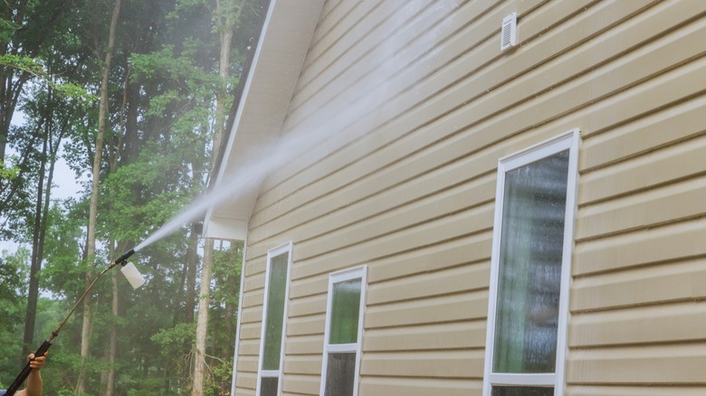 Someone power washing house walls