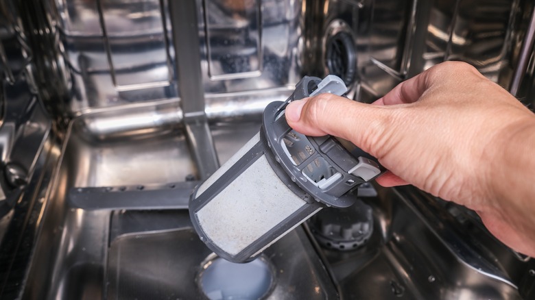 hand taking dishwasher filter out