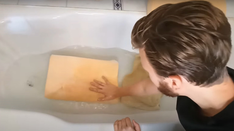 man washing pillow in bathtub