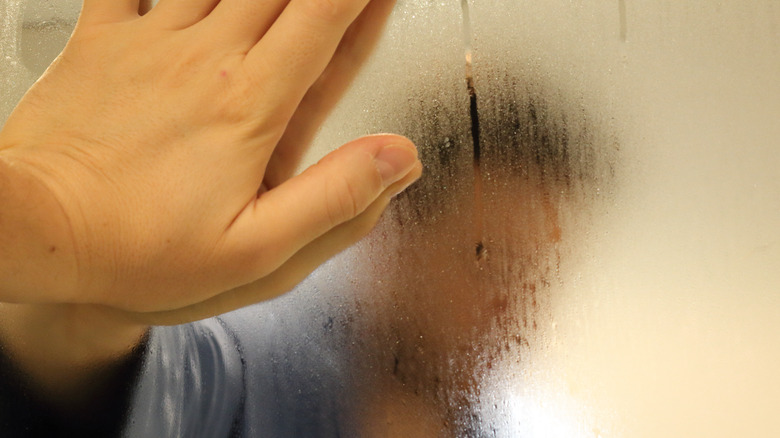 Man touching foggy bathroom mirror