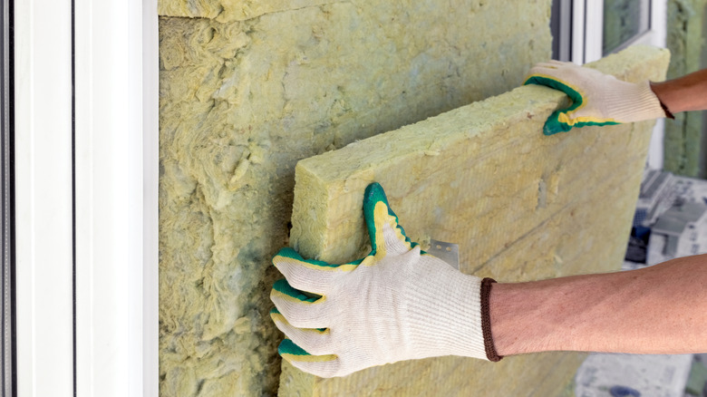 A builder installs mineral sheet for heat insulation