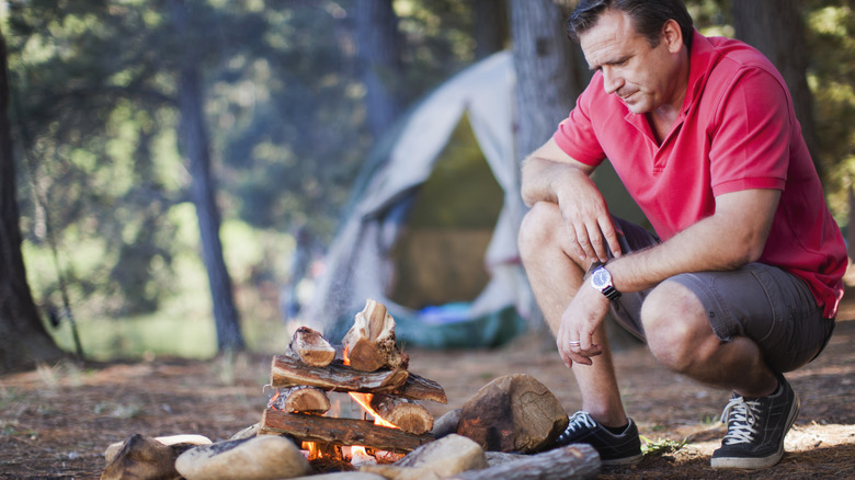 Man building campfire with wood