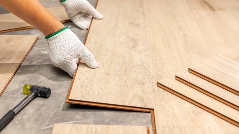 Person laying laminate floor planks on the ground